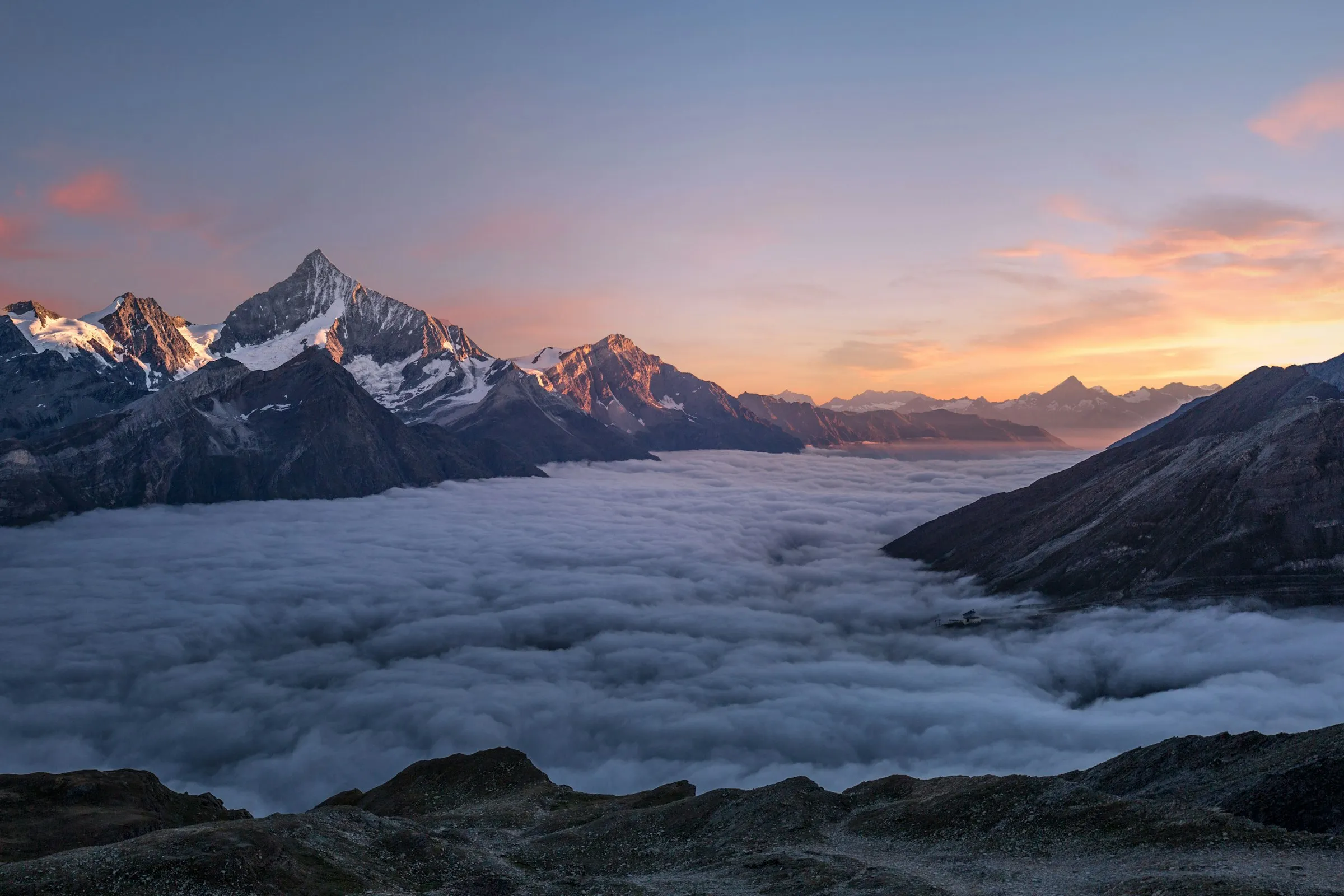 Sunrise over mountain peaks rising above a sea of clouds