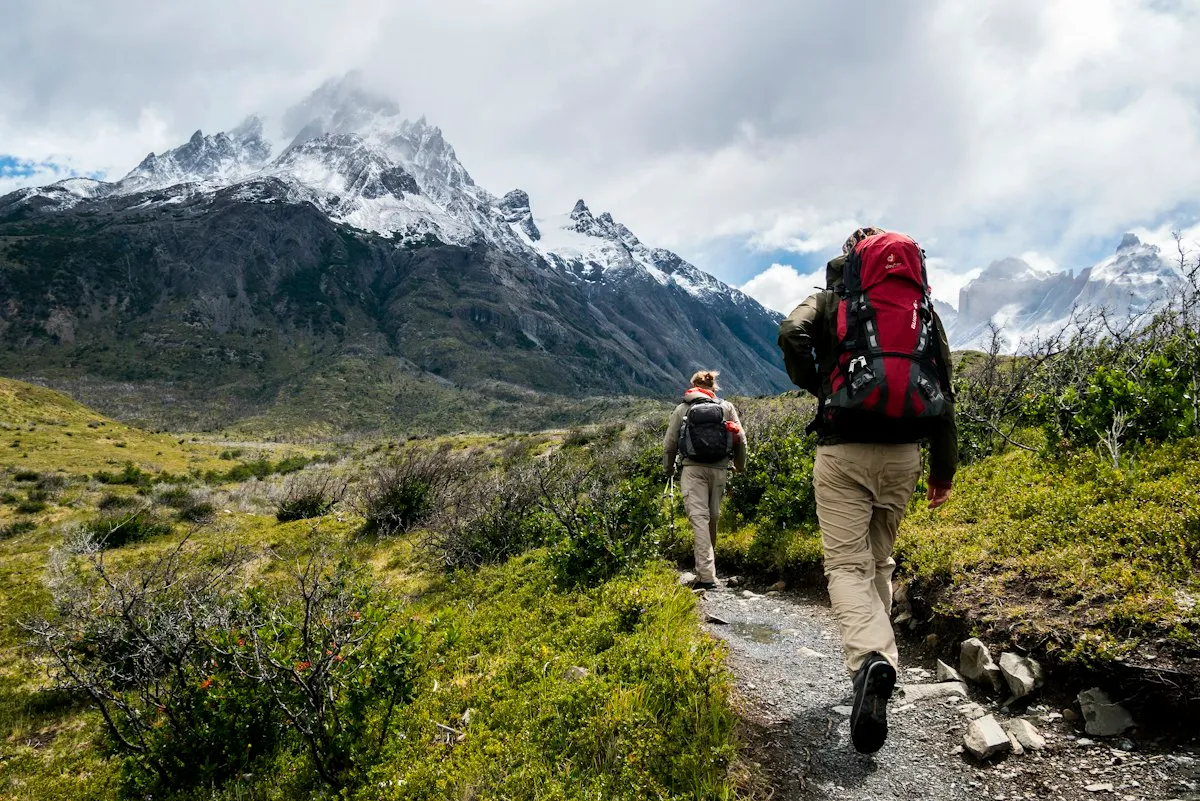Two hikers with backpacks walking a mountain trail